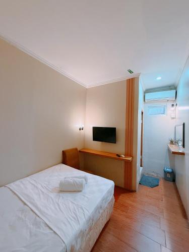 a bedroom with a white bed and a flat screen tv at URVANA Hotel By Majestra Hospitality in Kamparganya