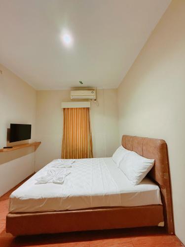 a small bedroom with a bed and a television at URVANA Hotel By Majestra Hospitality in Kamparganya
