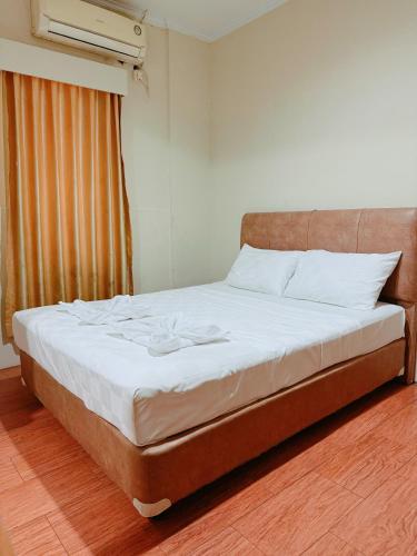 a bedroom with a bed with white sheets and a window at URVANA Hotel By Majestra Hospitality in Kamparganya