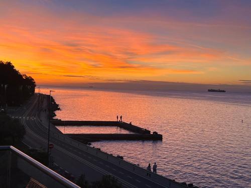 a sunset over the water with people walking on a pier at Relax vila žusterna in Koper