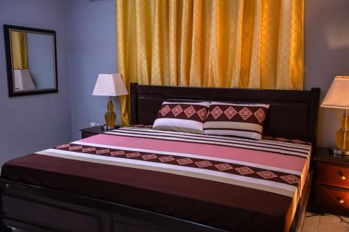 a bedroom with a bed with two lamps and a mirror at Rapid City Guest House Accra in Oshiyie