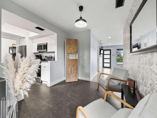 a living room with a couch and chairs and a kitchen at Luxury Stay with Filtered Water & Pet-Friendly Fun in Fort Lauderdale