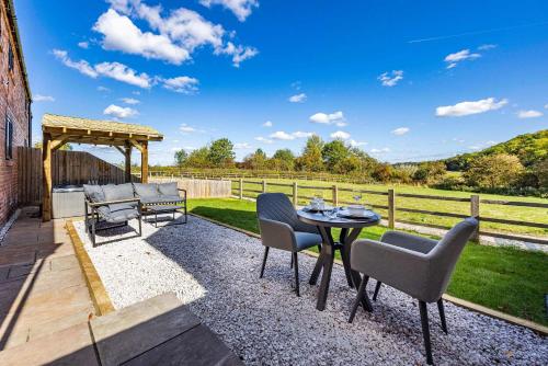a patio with a table and chairs and a gazebo at Gorgeous Barn with Hot Tub and Games Room in Bunny