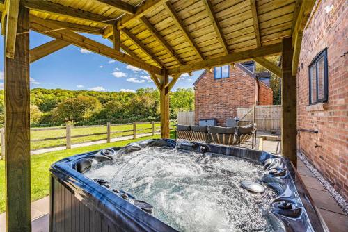 a hot tub on the patio of a house at Gorgeous Barn with Hot Tub and Games Room in Bunny