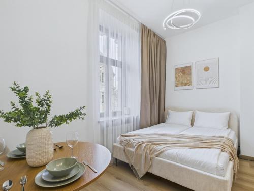 a white bedroom with a bed and a table at M4 Modern City Centre Studios - 3 min Central Station in Riga