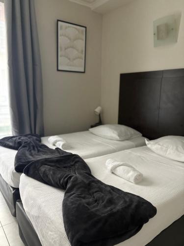 two beds in a hotel room with black blankets at HOTEL DU MONT LOUIS in Paris