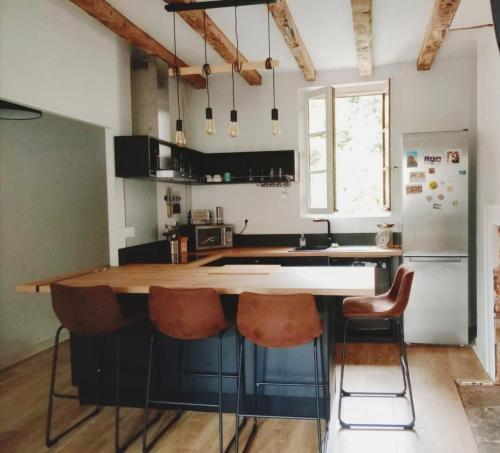 a kitchen with a counter with chairs and a refrigerator at L horizon d Aristide - 1 Chambre in Tulle