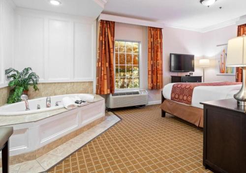 a hotel room with a bed and a tub and a bed and a television at The Wilshire Grand Hotel in West Orange