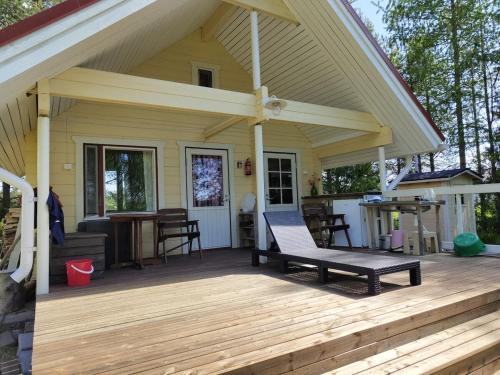 a porch of a house with a bench on a deck at Toivon pieni rantamökki in Sonka