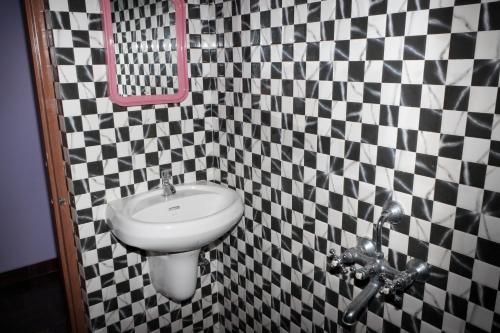 Un baño con lavabo y pared a cuadros blancos y negros. en Vincent's Holiday Home, en Baga