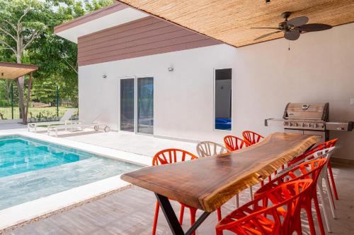 a dining room with a table and chairs next to a pool at Villa Blanca in Esterillos Este
