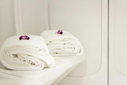two white towels with purple flowers on them on a shelf at Al Diar Sawa Hotel Apartments in Abu Dhabi