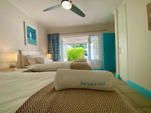 a bedroom with two beds and a ceiling fan at Sea and Soul, River Club Villa in Plettenberg Bay
