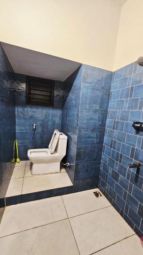 a bathroom with a toilet in a blue tiled wall at Shree Gowthameshwara Nilaya in Chikmagalūr