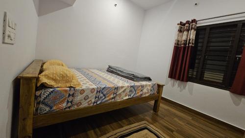 a small bed in a room with a window at Shree Gowthameshwara Nilaya in Chikmagalūr