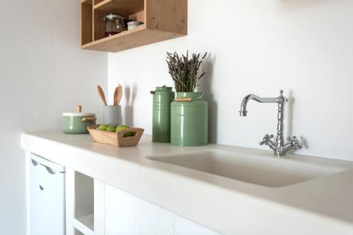a kitchen counter with a sink and green containers at Seven Suites in Glinado Naxos