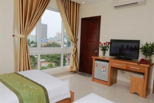 Un dormitorio con una cama y un escritorio con televisión. en Jolilian Hotel Bãi Sau, en Vung Tau