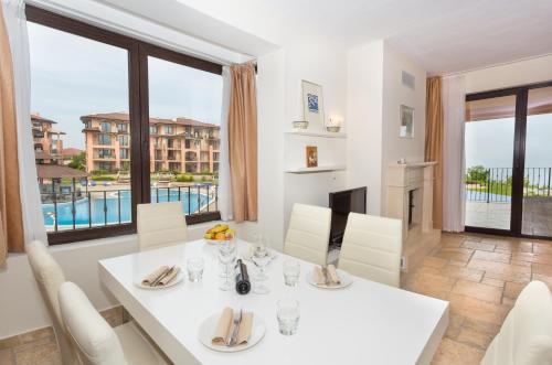 a dining room with a white table and chairs and a large window at Kaliakria Resort in Topola