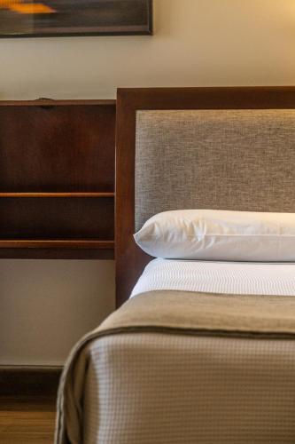a bed with a brown headboard and a white pillow at Hotel Almería in Salta