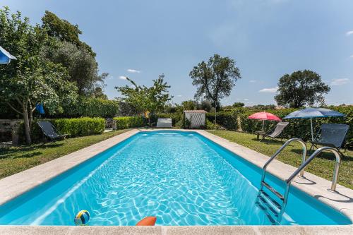 a swimming pool in a yard with an umbrella at Sevenfarm Turismo Rural in Mangualde