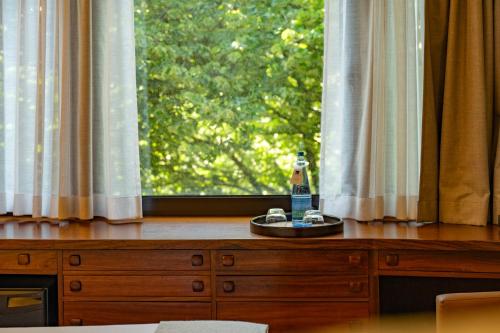 a bottle of alcohol on a wooden dresser in front of a window at Hotel Dom Carlos Park in Lisbon