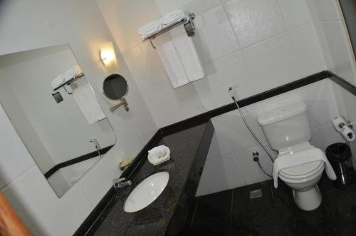 a white bathroom with a toilet and a sink at Constantino Hotel e Eventos in Juiz de Fora