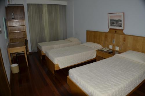a hotel room with two beds and a desk at Constantino Hotel e Eventos in Juiz de Fora
