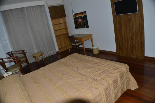 a bedroom with a bed and a desk in it at Constantino Hotel e Eventos in Juiz de Fora