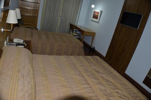 a hotel room with a bed and a desk at Constantino Hotel e Eventos in Juiz de Fora