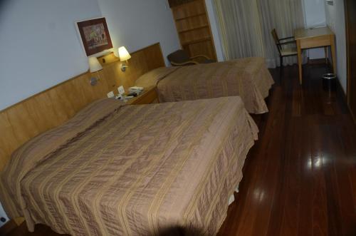 a hotel room with two beds and a wooden floor at Constantino Hotel e Eventos in Juiz de Fora