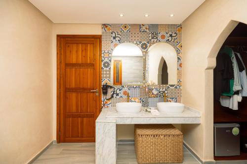 a bathroom with two sinks and a wooden door at Villa Stevana in Oulad Mazoug