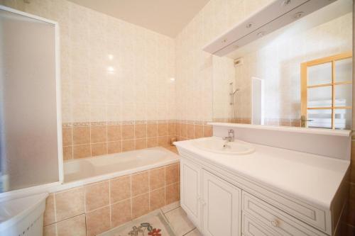 y baño con bañera, lavabo y bañera tubermottermott. en Chez Félicie - 2 grands gîtes, en Albepierre