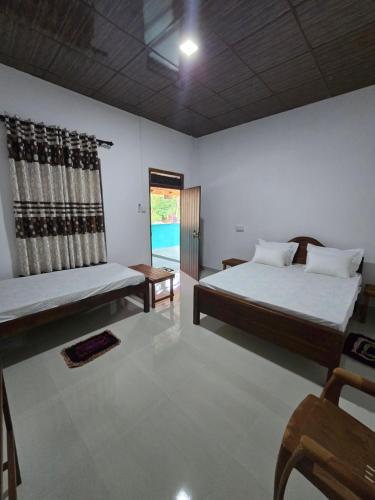 a large room with two beds and a window at Veenora Wild - Guest House in Anuradhapura