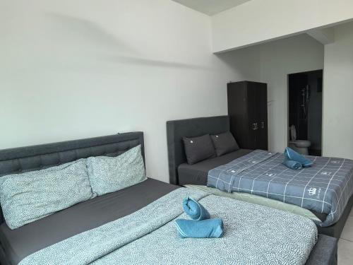 two beds with blue pillows on them in a room at Cozy&Comfy Suite Room Perai in Perai