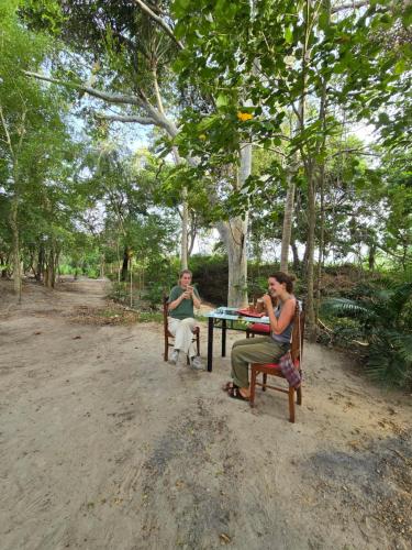 two women sitting at a picnic table with a dog at Veenora Wild - Guest House in Anuradhapura