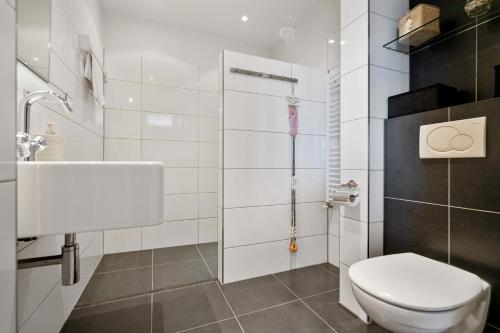 a white bathroom with a toilet and a sink at Appartement De Kokkel Free Parking in Zandvoort
