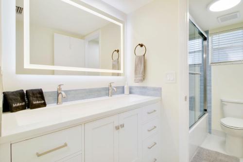 a white bathroom with a sink and a mirror at Steps To Beach! 4 Condos In 1- Perfect For Groups in West Palm Beach