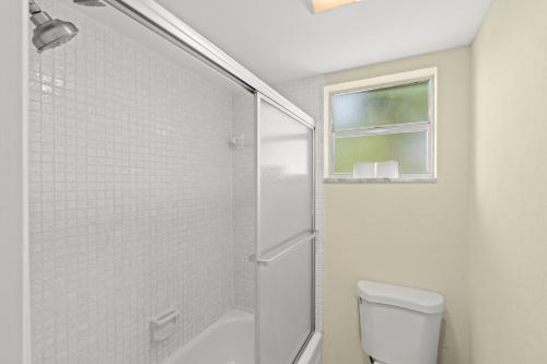 a white bathroom with a shower and a toilet at Steps To Beach! 4 Condos In 1- Perfect For Groups in West Palm Beach