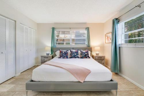 a bedroom with a bed and two windows at Steps To Beach! 4 Condos In 1- Perfect For Groups in West Palm Beach