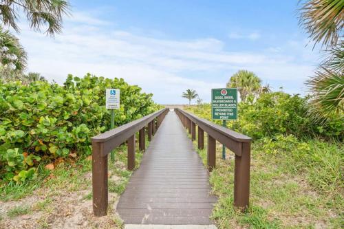 a wooden bridge over a field with signs on it at Steps To Beach! 4 Condos In 1- Perfect For Groups in West Palm Beach