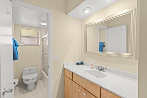 a bathroom with a sink and a toilet and a mirror at Steps To Beach! 4 Condos In 1- Perfect For Groups in West Palm Beach