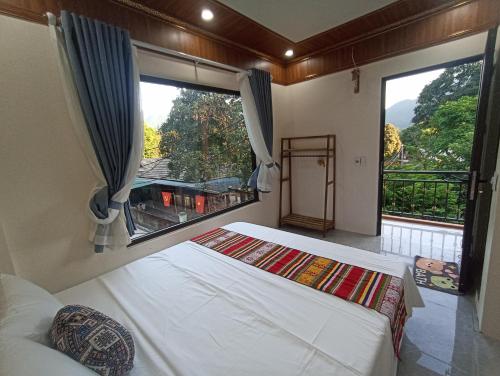 a bedroom with two beds and a large window at Thao Ly Homestay Mai Chau in Hòa Bình