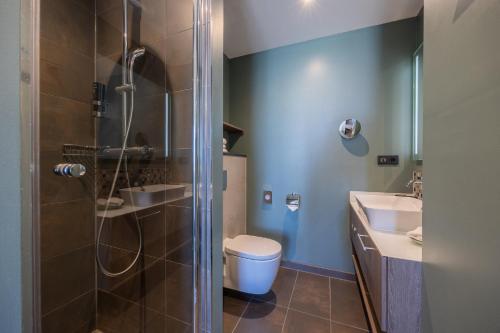 a bathroom with a shower and a toilet and a sink at Leonardo Royal Hotel Amsterdam in Amsterdam