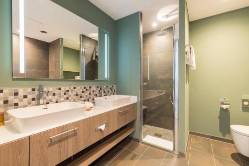 a bathroom with a sink and a shower at Leonardo Royal Hotel Amsterdam in Amsterdam