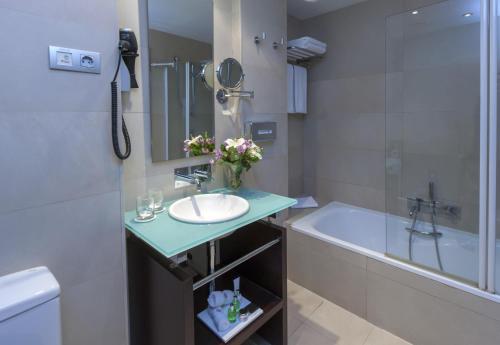 a bathroom with a sink and a bath tub at NH Collection Sevilla in Seville
