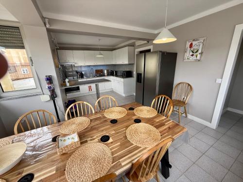 a kitchen with a wooden table with chairs and a refrigerator at Home in Paradise Costa de Lavos in Costa de Lavos