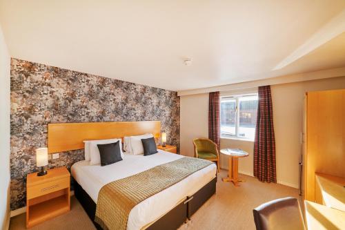 a hotel room with a bed and a desk at The Barn Hotel & Spa in Grantham