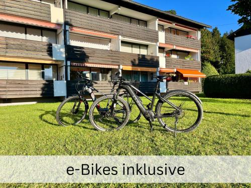 deux vélos garés dans l'herbe devant un bâtiment dans l'établissement BERGFEX Ifenblick mit eBikes und Sommer-Bergbahnticket, à Oberstdorf