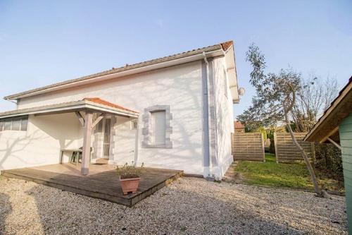 a white house with a porch and a wooden deck at Le bourg 2 in Mimizan