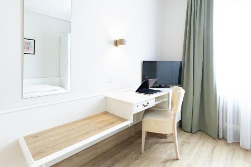 a room with a desk with a computer and a mirror at Garner Hotel Aschaffenburg Post by IHG in Aschaffenburg